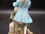 une figurine représentant une femme en robe bleue et chapeau