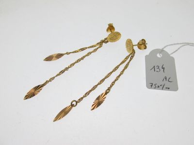 une paire de boucles d'oreilles plaquées or et une étiquette sur fond blanc