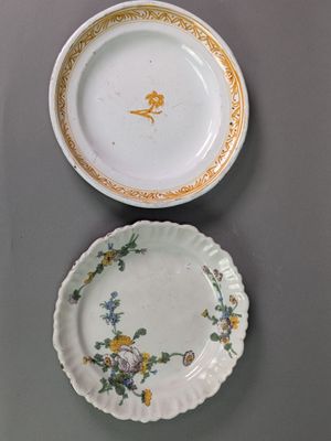 deux assiettes et un bol posés sur une table, avec une horloge en arrière-plan