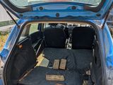 the back of a blue car with its trunk open on the grass