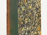 an old book with a green cover sitting on top of a white table