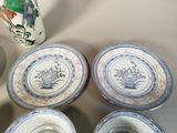 four blue and white plates and a vase on a table