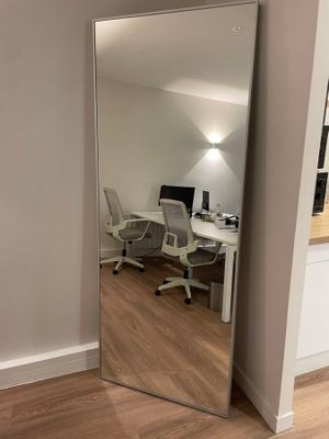 un miroir dans un coin d'une pièce où se trouvent un bureau et une chaise