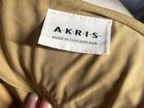 an image of a person holding a tan jacket with a label on it