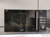 quelqu'un prend une photo d'un micro-ondes dans lequel on voit son reflet
