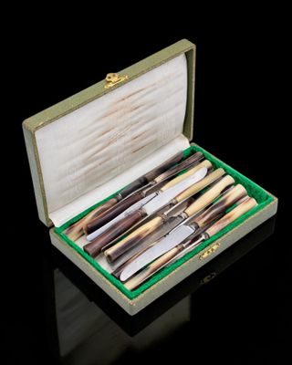 a box with a set of knives in it on a black surface