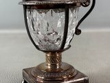 a small silver cup with a handle on a table