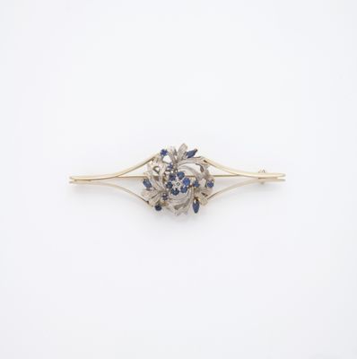 un gros plan sur une broche en forme de fleur, sertie de diamants et de saphirs