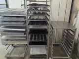 many trays of food on a metal rack in a kitchen