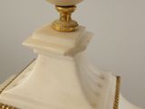 a white vase with a gold rim on top of a white pedestal