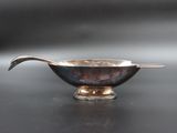 a silver bowl with a spoon in it on a table