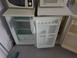 a small refrigerator with a microwave on top of it