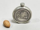 a silver flask with a picture of a man and a dog on it