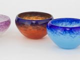 cinq vases en verre de couleurs différentes posés sur une surface blanche
