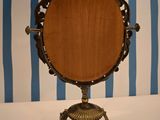 a mirror on a stand with a blue and white striped wall behind it