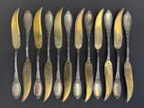 huit cuillères et six fourchettes en métal argenté sont alignées sur une surface noire
