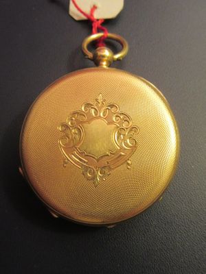 a gold pocket watch with a red string around it