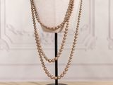 a close up of a mannequin with a gold bead necklace on it