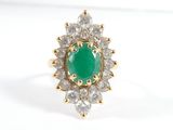 gros plan d'une bague avec une pierre verte entourée de diamants