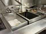 stainless steel counter top in a commercial kitchen with two pans of food