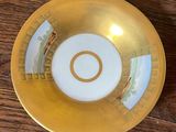an image of a gold and white bowl sitting on a wooden table