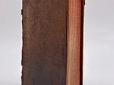 an old book with a brown cover sitting on top of a white surface