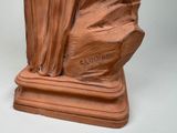 statue of a woman sitting on a rock with her hands in her pockets