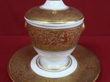 an image of a gold and white bowl and saucer on a red background