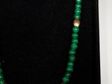 a close up of a green necklace with a gold clasp
