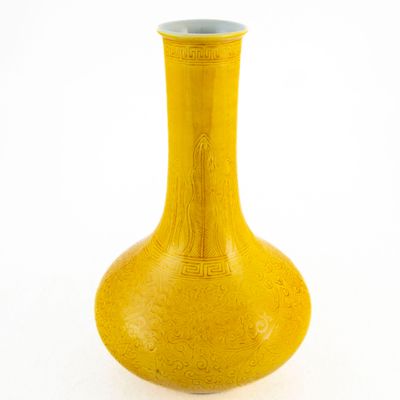 un vase jaune posé sur une surface blanche