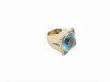 a close up of a gold ring with a blue topaz stone