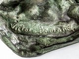 a bronze statue of a dog on a white surface