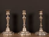 trois bougeoirs en argent posés sur une table en bois