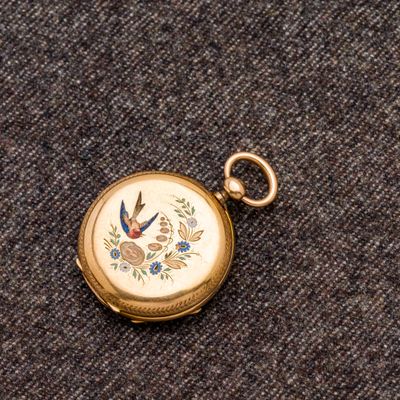 une petite montre de poche en or ornée d'un oiseau