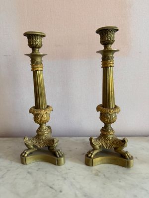 une paire de bougeoirs anciens en laiton posés sur une table en marbre