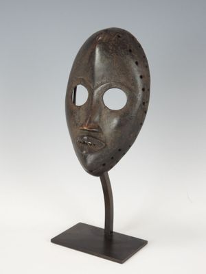 un masque en bronze posé sur un socle, sur fond blanc