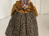doll dressed in a dress and bonnet with a plaid hat