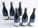 six bottles of wine are lined up in a row on a white surface