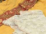 two pieces of clothing on a bed with a red and yellow blanket