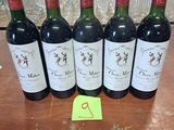 six bouteilles de vin rouge sont alignées sur une table
