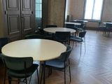 des tables et des chaises dans une pièce dotée d'un parquet et de grandes fenêtres