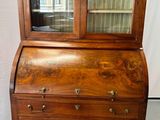 un vieux secrétaire en bois avec des portes vitrées et des tiroirs