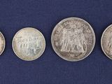 four different types of silver coins on a blue cloth