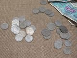 a lot of coins on the table next to a bag of money