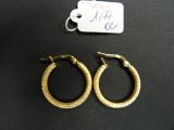 deux paires de boucles d'oreilles créoles en or posées sur une surface noire, accompagnées d'une étiquette de prix