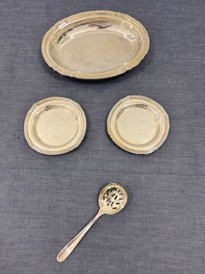une assiette en argent avec une cuillère et un repose-cuillère posés sur une table