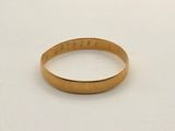 gros plan d'une bague en or sur une surface blanche