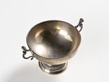 a silver cup with a handle on a white surface