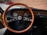 the steering wheel and dashboard of a classic car in a parking lot