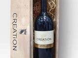 the bottle of wine is in a wooden box on a white surface